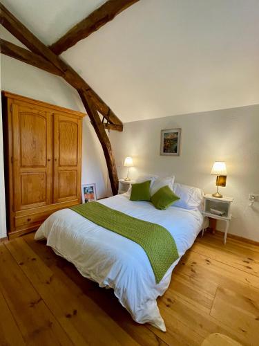a bedroom with a large white bed with green pillows at La Chartreuse de Tom in Saint-Aubin-de-Nabirat