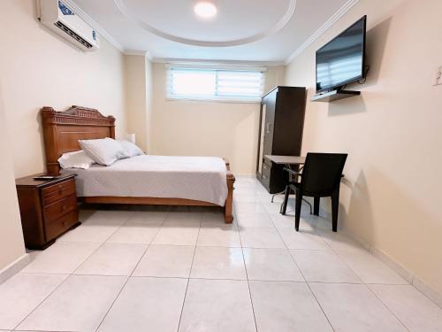 Dormitorio con cama, escritorio y TV en Suitesecu Guayaquil en Guayaquil