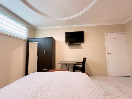 1 dormitorio con cama, mesa y TV en Suitesecu Guayaquil en Guayaquil
