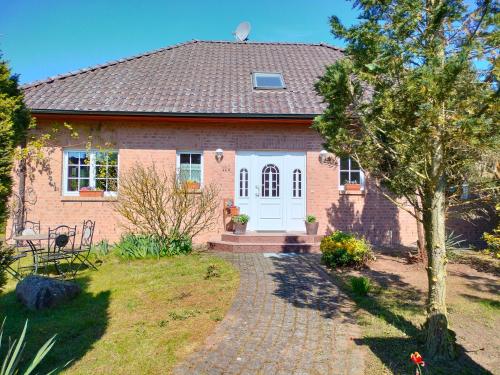 ein rotes Backsteinhaus mit einer weißen Tür in der Unterkunft Ferienhaus Belle - FEWO Rose in Daschow