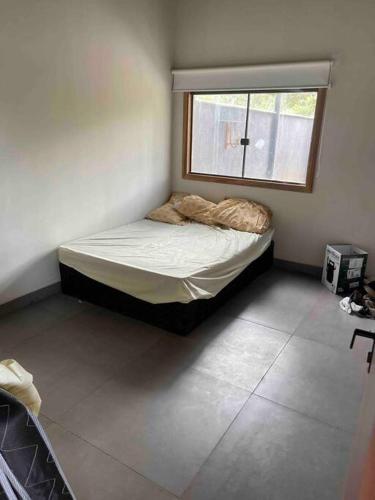 uma pequena cama num quarto com uma janela em Sitioalocomotiva em Jequitibá
