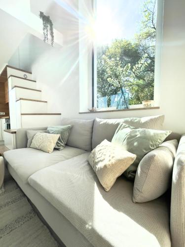 ein weißes Sofa im Wohnzimmer mit Fenster in der Unterkunft Tiny House Wettelsheim in Treuchtlingen