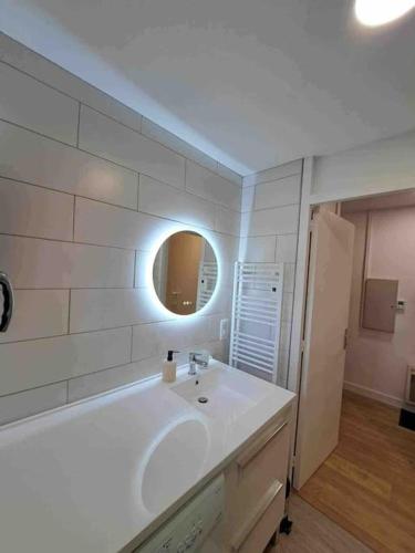 une salle de bain blanche avec un lavabo et un miroir dans l'établissement Havre de paix cures thermales, à Dax