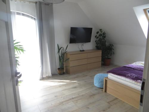 a bedroom with a bed and a flat screen tv at Dom z widokiem na jezioro in Chrostkowo
