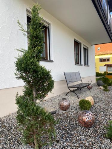 a chair and a pine tree in front of a building at Idyllische Ferienwohnungen in Mossendorf in Burglengenfeld
