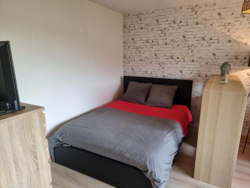 une chambre avec un lit et un mur de briques dans l'établissement Le Lumineux, à Rodez