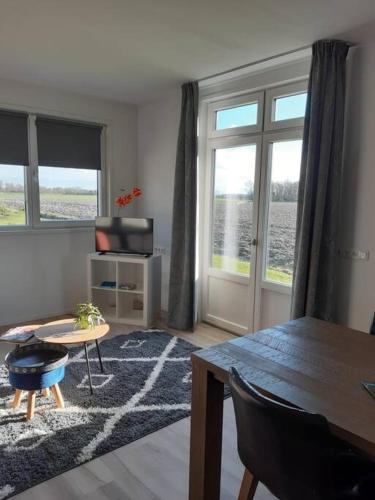 a living room with a dining room table and a room with windows at B&B weidse blik Ingelum in Engelum