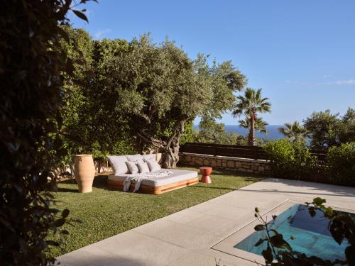 a couch sitting in the grass next to a tree at Cielo villas - An Authentic Mediterranean Living in Zakynthos Town