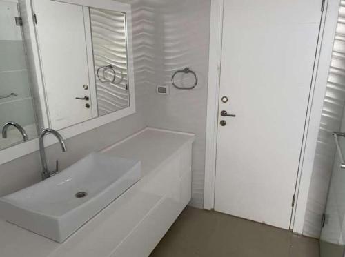 La salle de bains blanche est pourvue d'un lavabo et d'un miroir. dans l'établissement וילה הנסיכה ‏‏, à Mitzpe Ramon