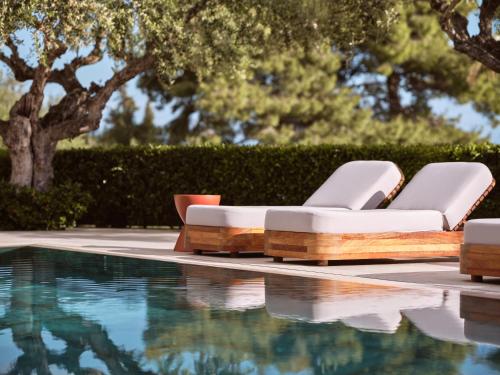 a pool with two lounge chairs next to a swimming pool at Cielo villas - An Authentic Mediterranean Living in Zakynthos Town
