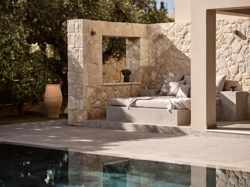 a patio with a swimming pool next to a stone wall at Cielo villas - An Authentic Mediterranean Living in Zakynthos Town