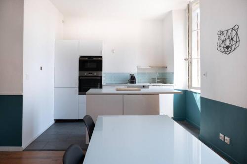 a kitchen with white cabinets and a table with chairs at T2 La Joliette, 13002 Marseille in Marseille