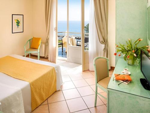 a hotel room with a bed and a view of the ocean at Hotel Eden Park in Diano Marina