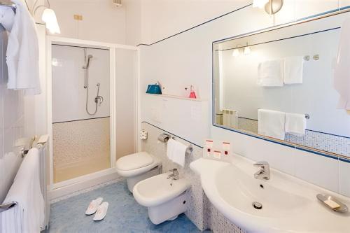 Baño blanco con lavabo y aseo en Hotel Eden Park, en Diano Marina