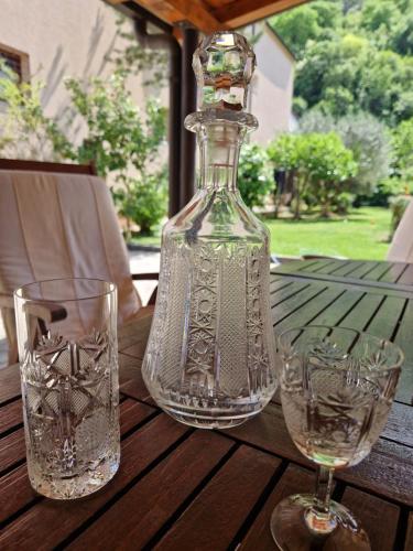 eine Glasflasche auf einem Tisch mit zwei Gläsern in der Unterkunft Apartman Mona in Mostar