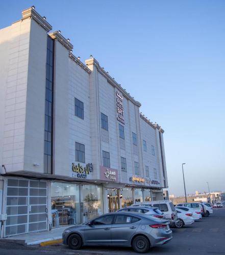 a large building with cars parked in a parking lot at شقق بيت المدينة للشقق المخدومة in Al Madinah