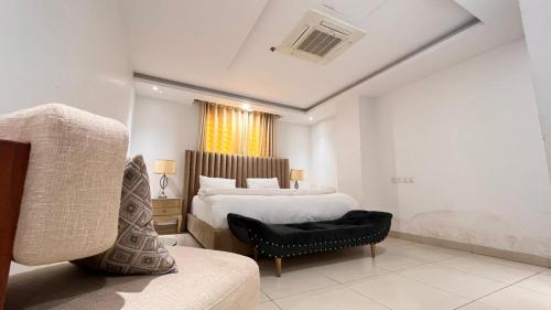 - une chambre avec un lit, une chaise et un canapé dans l'établissement Luxurious Two bedroom Apartment In Gold Crest Mall And Apartment's, à Lahore