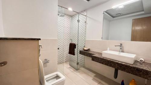 La salle de bains est pourvue d'un lavabo, de toilettes et d'un miroir. dans l'établissement Luxurious Two bedroom Apartment In Gold Crest Mall And Apartment's, à Lahore