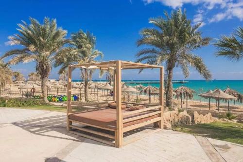 a swing at a beach with palm trees and the ocean at Lasirena mini egypt elsokhna in Ain Sokhna