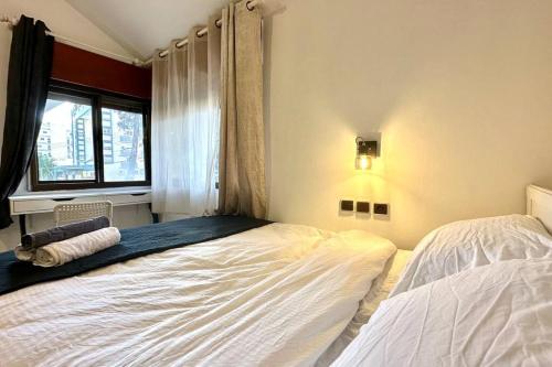 a bedroom with two beds and a window at Studio in the center with BBQ Patio and parking in Nahariyya