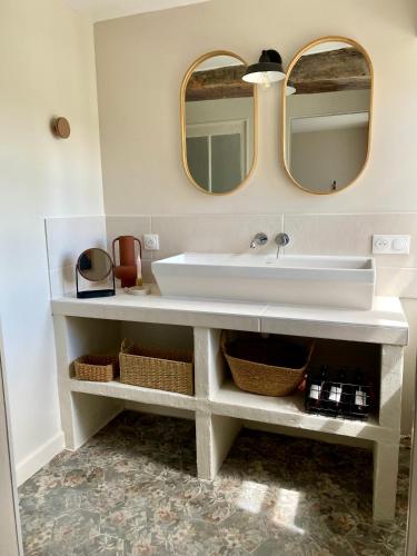 une salle de bain avec un lavabo blanc et deux miroirs dans l'établissement gite seccotine, à Saint-Mard-de-Vaux