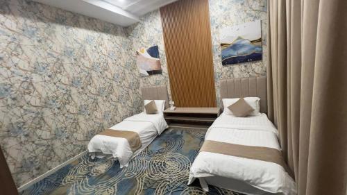 two twin beds in a room with a wall at شقق بيت المدينة للشقق المخدومة in Al Madinah