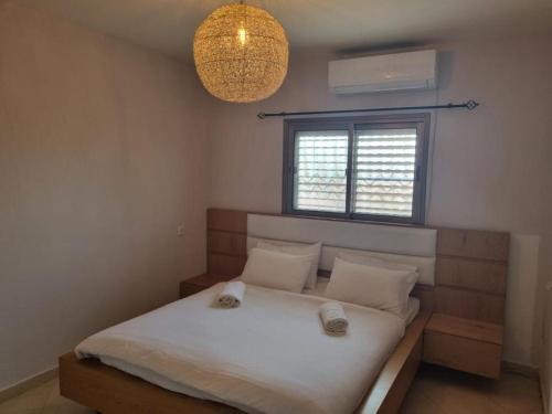 Schlafzimmer mit einem Bett mit weißer Bettwäsche und einem Fenster in der Unterkunft צימר רמון in Mitzpe Ramon