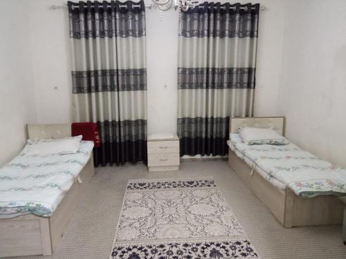 twee bedden in een kamer met gordijnen en een tapijt bij apartment camfort small in Tasjkent