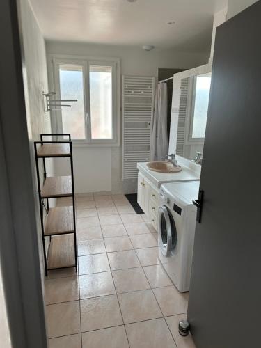 a bathroom with a washing machine and a sink at La Maison des vendangeurs in Grauves