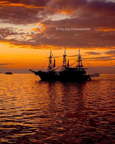 a pirate ship in the ocean at sunset at Queen Suites Family Friendly 60m2 in Thessaloniki