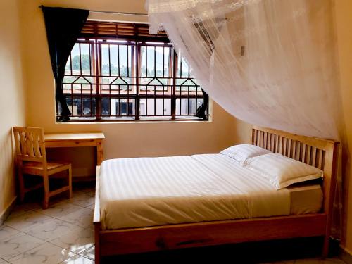 a bedroom with a bed and a desk and a window at Mianzi Guest House in Kisoro
