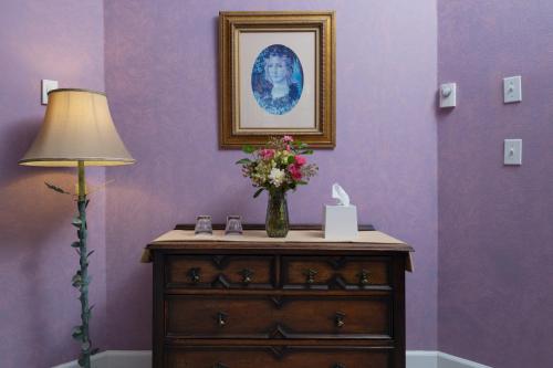 a vase of flowers on a dresser next to a lamp at Arch Cape Inn and Retreat in Arch Cape
