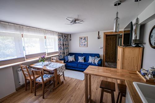 uma sala de estar com uma mesa e um sofá azul em Zacisze Pod Reglami em Zakopane