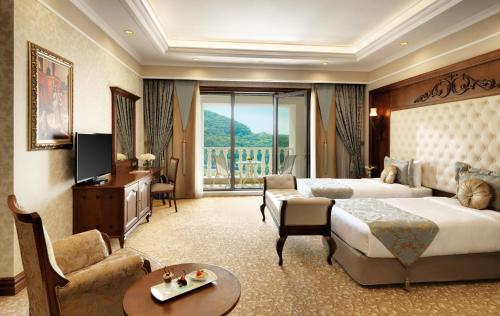 a hotel room with a bed and a couch and a television at Shamakhi Palace Sharadil in Şǝrǝdil