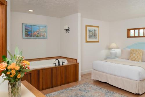 a bedroom with a bed and a tub and a bed at Arch Cape Inn and Retreat in Arch Cape