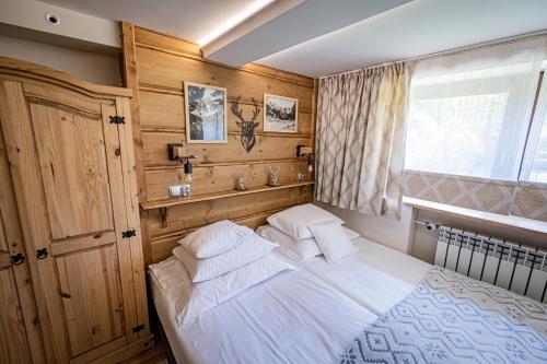 1 dormitorio con cama blanca y ventana en Zacisze Pod Reglami, en Zakopane