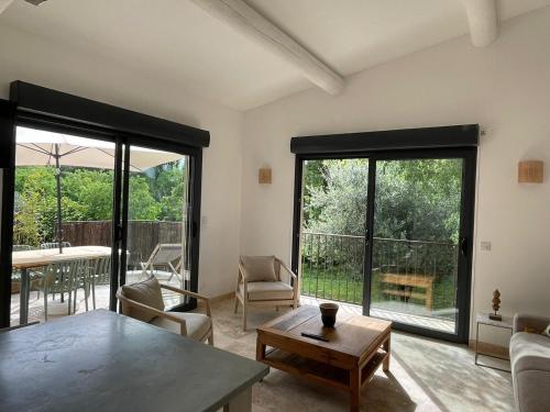 a living room with a table and chairs and windows at La maison d'HamiH "Gîte et Chambres d'hôtes in Uzès