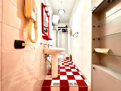 baño con lavabo y suelo a cuadros rojo y blanco en Casa del Sole, en Campofelice di Roccella