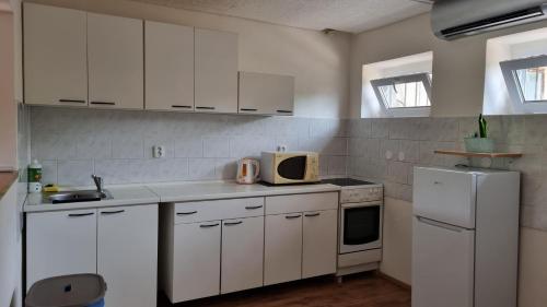 uma cozinha com armários brancos e um frigorífico branco em Apartmány Vinařství Klučov em Lstiboř
