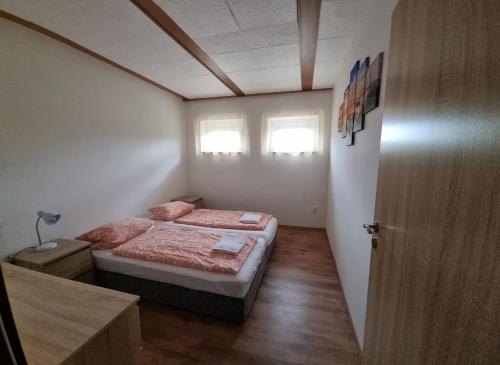um pequeno quarto com uma cama e 2 janelas em Apartmány Vinařství Klučov em Lstiboř