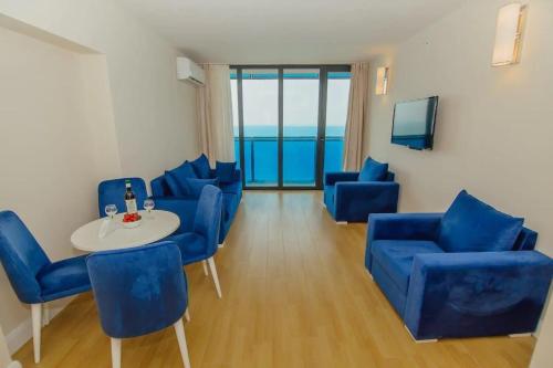 a living room with blue chairs and a table at Orbi City with Sea View in Batumi