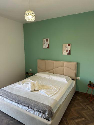 a bed in a bedroom with a green wall at Stormi's Apartament in Pogradec