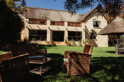 a house with chairs and a table in the yard at Blue Hills Lodge in Midrand