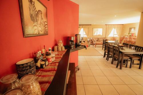 a kitchen with red walls and tables and chairs at Blue Hills Lodge in Midrand