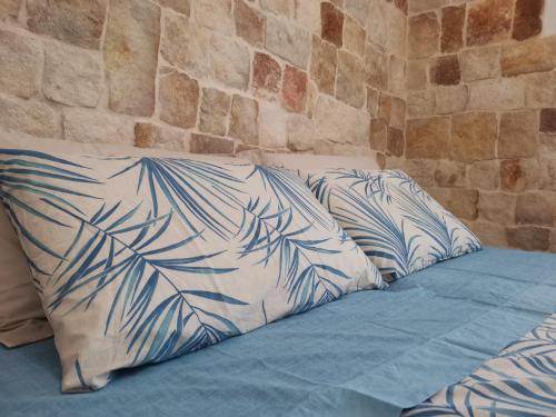 ein Bett mit blauen und weißen Kissen neben einer Wand in der Unterkunft Villa Su Monte Abele in Selva di Fasano