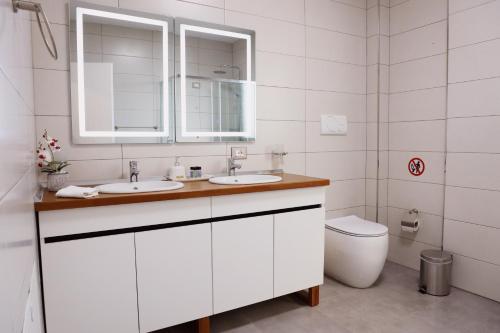 a white bathroom with two sinks and a toilet at Rajmonda Apartment in Lezhë