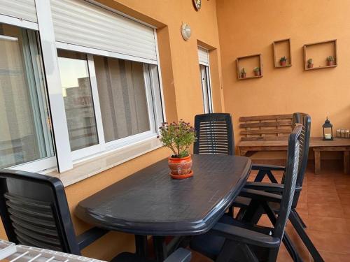 une table noire avec des chaises et une table avec des fleurs. dans l'établissement Apartament Els Flamencs, à Els Muntells