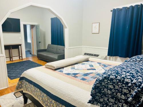 1 dormitorio con cama, sofá y cortinas azules en The Tellico Plains Inn and Event Venue en Tellico Plains