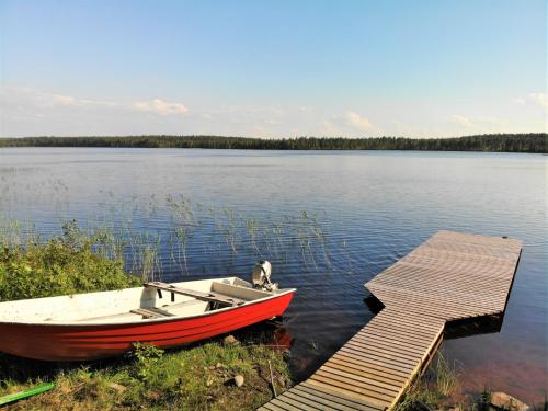 a boat sitting next to a dock on a lake at Lomamökki Kuhmo, Tervatörmä in Kuhmo