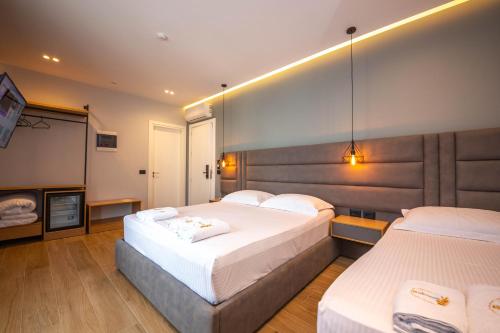 a hotel room with two beds and a television at Absolute Hotel Ksamil in Ksamil